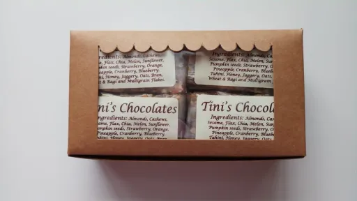 Brown cardboard box with a scalloped window displaying four cereal bars with labels.